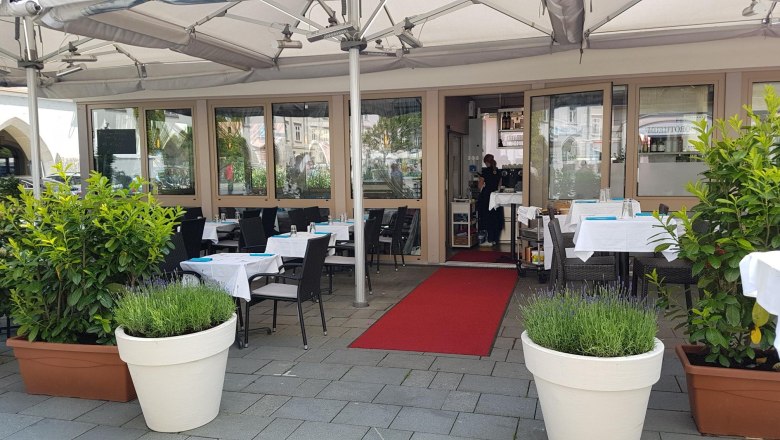 Reef & Beef with sidewalk café, © Piroska Weiss Outdoor area of a restaurant with laid tables and plants.