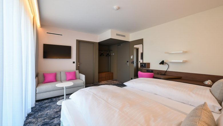 Suite with a view of the Schneeberg, © Philipp Blickfang Modern hotel suite with double bed, sofa, TV and desk.