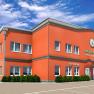 Hotel Winrooms in Wiener Neustadt, © Winrooms Betrieb GmbH Außenansicht des Hotel Winrooms in Wiener Neustadt mit orangefarbener Fassade und Uhr.