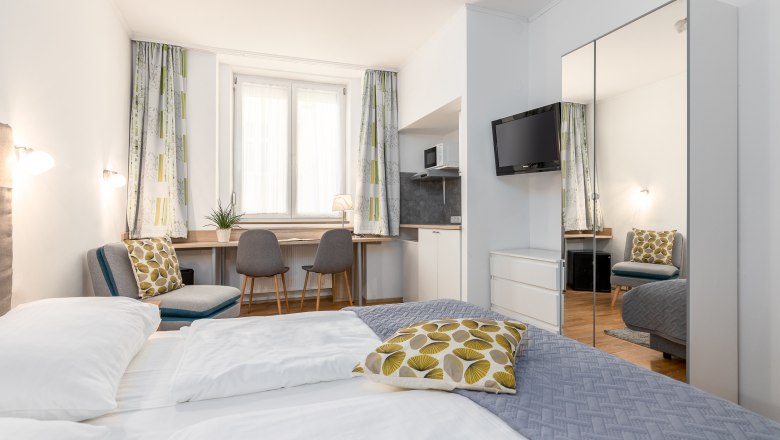 Hotel Zentral Doppelzimmer, © MartinHaider Fotografie/Hotel Zentral Schwartz GmbH Modernes Hotelzimmer mit Doppelbett, Schreibtisch, Stühlen und TV.