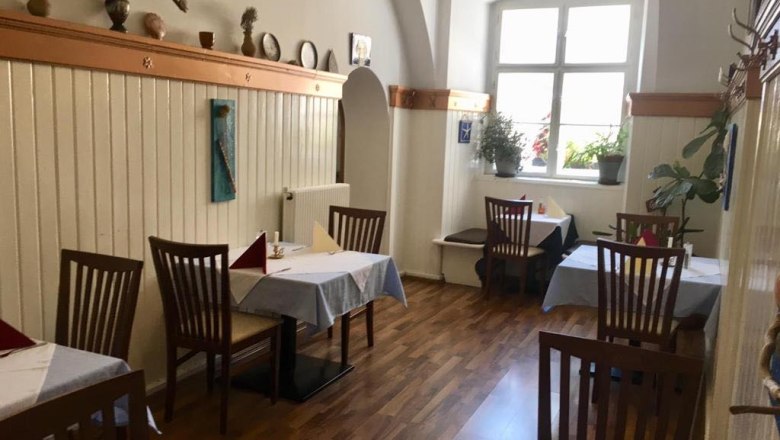 Innenansicht eines gemütlichen Restaurants mit Holzboden, Holzmöbeln und dekorierten Wänden.