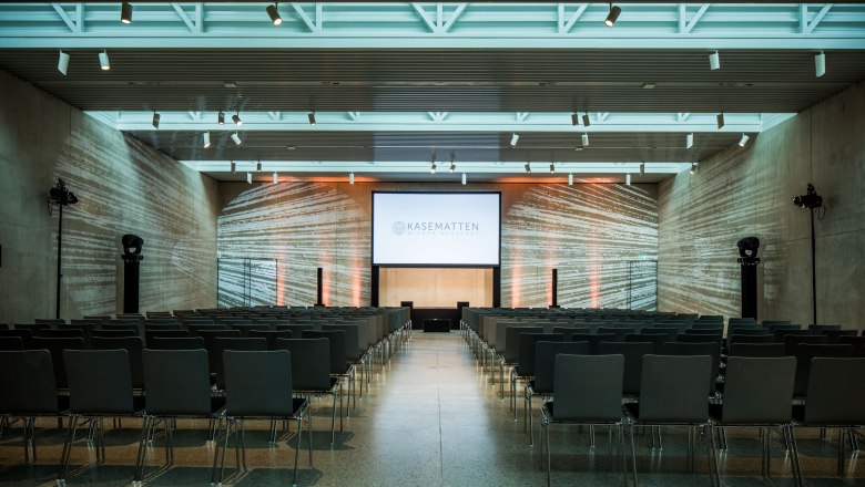 Modern concert hall with seating and screen.
