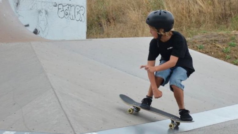 Ein Kind mit Helm fährt auf einem Skateboard in einem Skatepark.