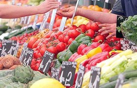 Marktstand mit frischem Gemüse und Obst, Hände beim Bezahlen.