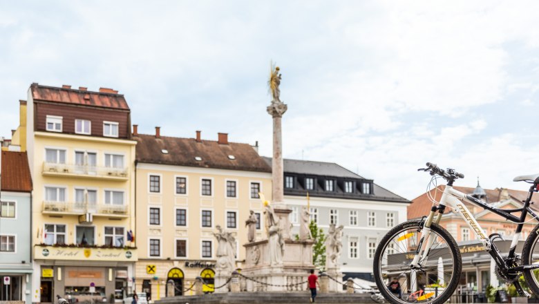 Stadtplatz mit Brunnen, Fahrrad im Vordergrund, Hotel Zentral im Hintergrund.