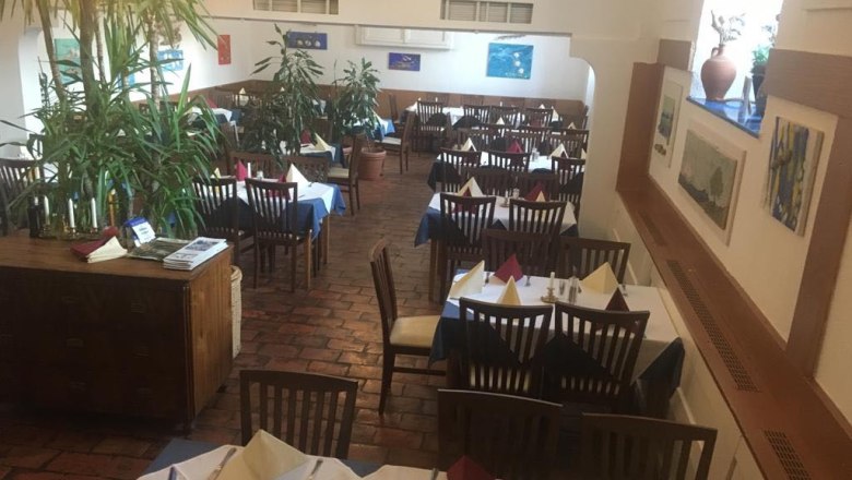 Innenansicht eines Restaurants mit gedeckten Tischen und Pflanzen.