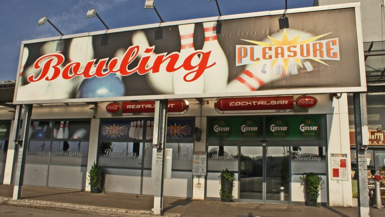 Eingang zu einem Bowlingcenter mit großem Schild 'Bowling Pleasureland'.