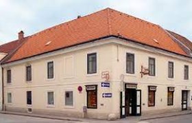 Eckgeb&auml;ude mit rotem Ziegeldach und mehreren Schildern, darunter eines mit der Aufschrift 'B&auml;ckerei'.