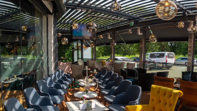 Moderne Terrasse mit blauen und gelben Sesseln, Glaskugelleuchten und Glasdach.