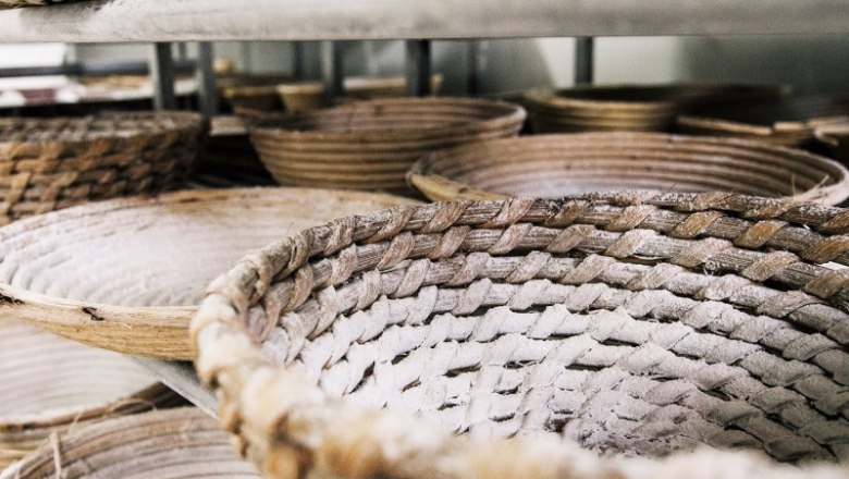 Geflochtene Brotkörbe mit Mehl bestäubt in einem Regal.