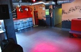 Innenansicht eines leeren Nachtclubs mit Bar, Hockern und Lüftungsrohren.