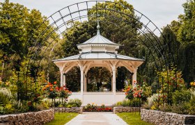 Wei&szlig;er Pavillon hinter Rosenbogen