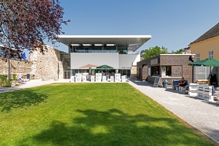 Moderner Gebäudekomplex mit Garten und Sitzbereich im Freien.