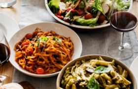 Ein Tisch mit Pasta, Salat und Rotwein.