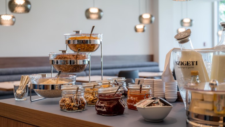 Frühstücksbuffet mit Müsli, Marmelade und Getränken.