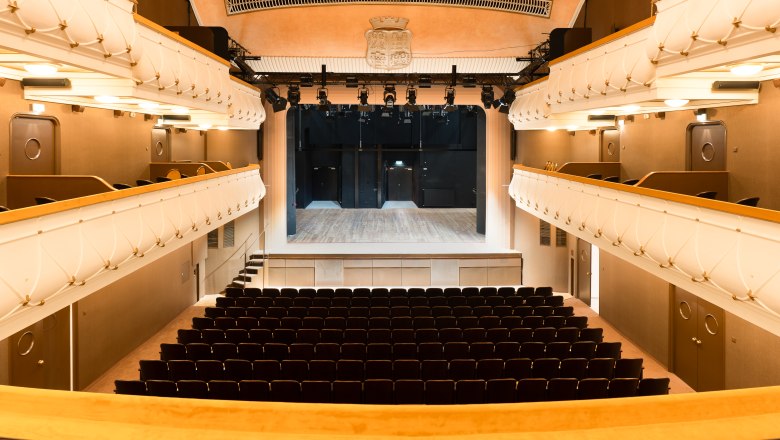 Innenansicht des prachtvollen Stadttheaters Wiener Neustadt mit goldgelben Samtsesseln, Logen und funkelndem Kronleuchter