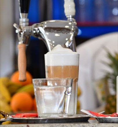 A glass of latte macchiato with foam next to a glass of water on a tray in a café.