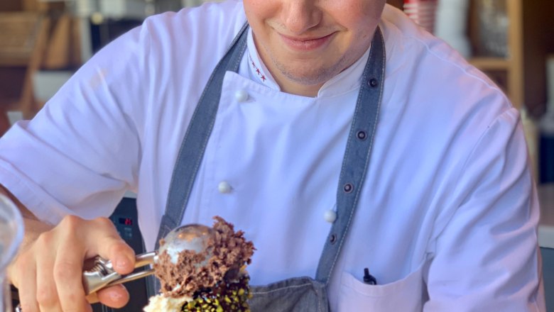 An ice cream vendor serves a pistachio cone with chocolate ice cream.