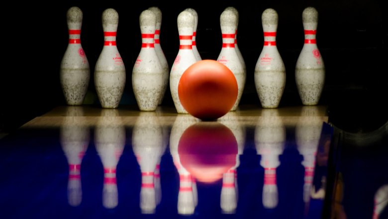 Eine Bowlingkugel rollt auf eine Gruppe von Kegeln zu.