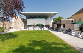 Moderner Gebäudekomplex mit Garten und Sitzbereich im Freien.