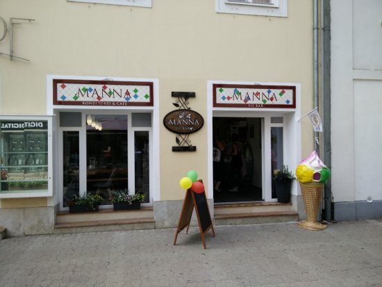 Eingang zur Manna Eisbar & Konditorei mit Schaufenstern und Eistüten-Dekoration.