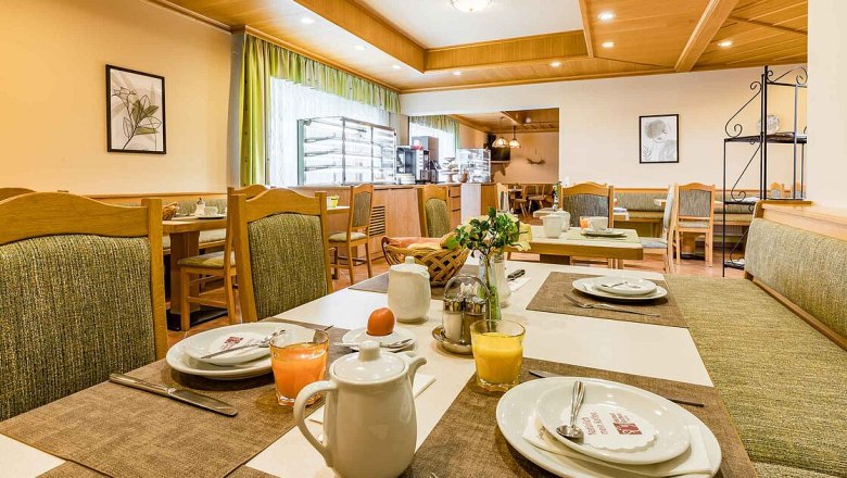 fruhstuck, © Hotel Garni Steinfeld Ein gemütlicher Frühstücksraum mit gedeckten Tischen, Saftgläsern und Kaffeekannen.