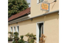 Außenansicht eines gelben Gebäudes mit einem Schild "Fratelli d'Italia Caffè-Pizza" und Pflanzen vor der Fassade.