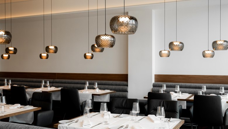 Modernes Restaurant mit eleganten Hängelampen und gedeckten Tischen.