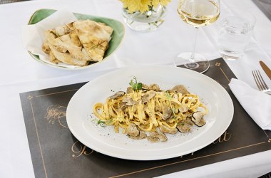Trüffelpasta mit Brot und Weißwein auf elegant gedecktem Tisch im Freien.