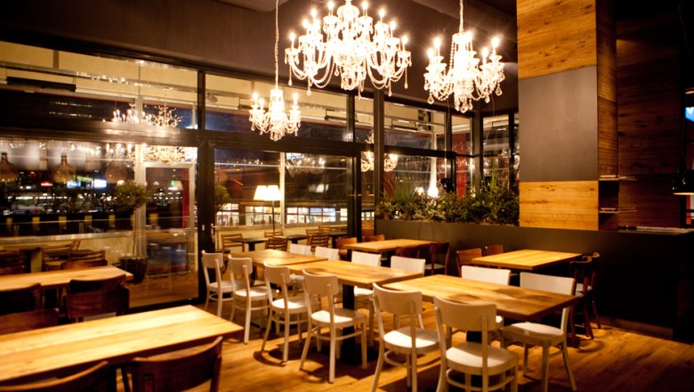 Innenansicht eines stilvollen Restaurants mit Kronleuchtern und Holzmöbeln.