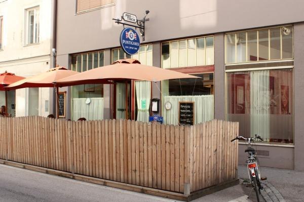 Außenansicht eines Cafés mit Holzzaun und Sonnenschirmen.