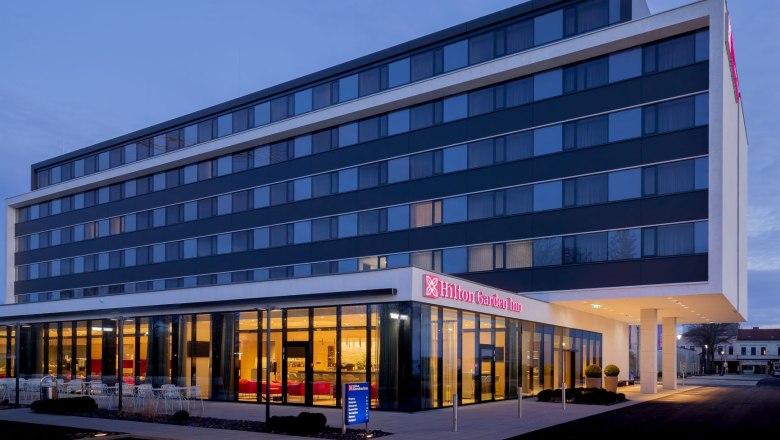 Hotel view, © Hilton Garden Inn Wiener Neustadt Exterior view of a modern hotel at dusk.