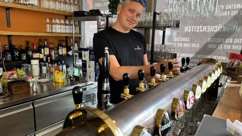 Ein Barkeeper zapft Bier an einer Theke mit mehreren Zapfhähnen in einer Bar.