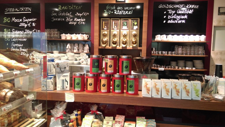 Interior view of a coffee roastery with coffee cans, cups and signs with coffee varieties.