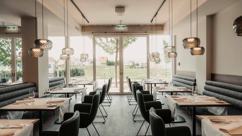Modernes Restaurant mit eleganter Einrichtung und großen Fenstern.