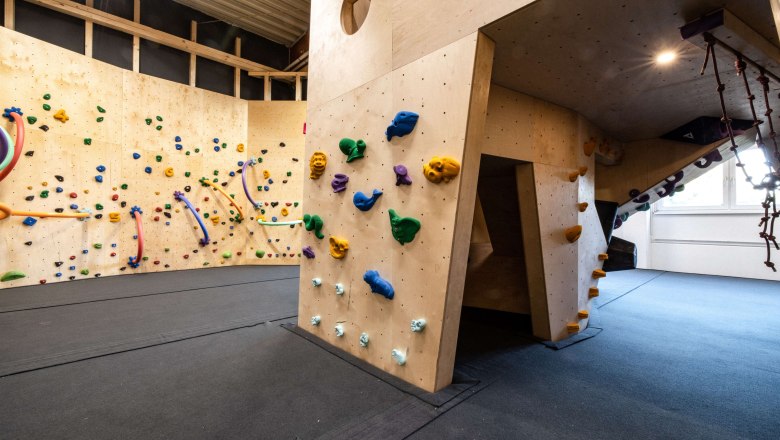 Innenansicht einer Kletterhalle mit bunten Klettergriffen an Holzwänden.