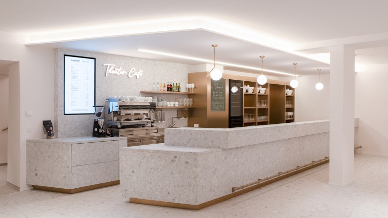 Modernes Theatercafé im Stadttheater Wiener Neustadt mit heller Steinoptik, stilvollen Lampen und einladender Bar