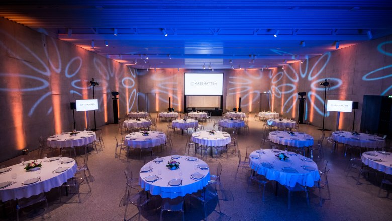 Elegant function room with round tables and blue lighting.