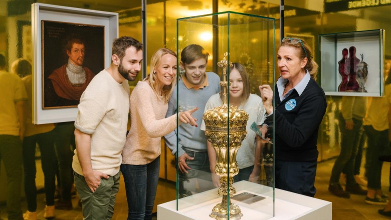 A group of people look at a golden trophy in a glass display case in a museum.