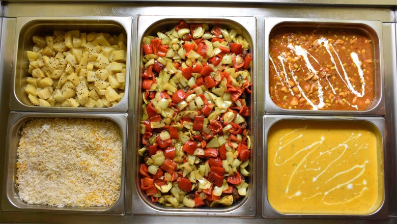 Various Indian dishes in metal containers. Including rice, potatoes, vegetables and various sauces.