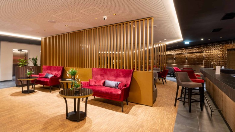 Moderne Hotellobby mit roten Sofas, Holzwänden und Pflanzen.