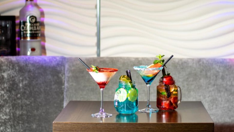 Drei bunte Cocktails auf einem Tisch in einer Bar.