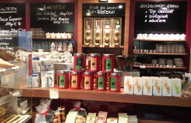 Innenansicht einer Kaffeerösterei mit Kaffeedosen, Tassen und Schildern mit Kaffeesorten.