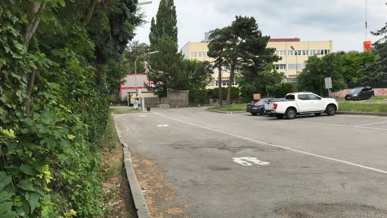Parking lot with cars and trees, buildings in the background.