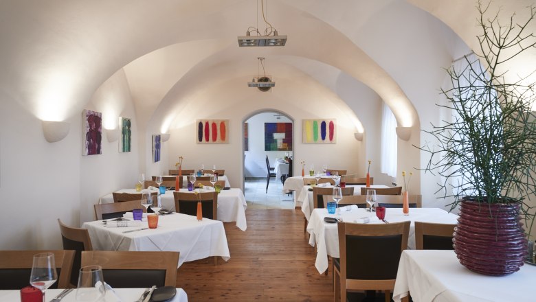 Ein elegantes Restaurant mit gewölbter Decke, weißen Tischdecken und bunter Dekoration.
