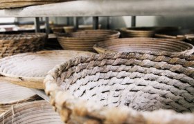 Geflochtene Brotkörbe mit Mehl bestäubt in einem Regal.