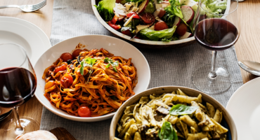 Ein Tisch mit Pasta, Salat und Rotwein.