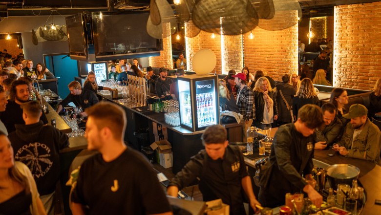 Menschen in belebtem Lokal Die Bar mit Backsteinwänden und stimmungsvoller Beleuchtung.