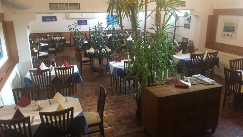 Innenansicht eines Restaurants mit Holzmöbeln und Pflanzen.