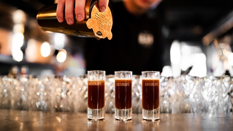 3 Shotgläser werden eingeschenkt mit Shaker
